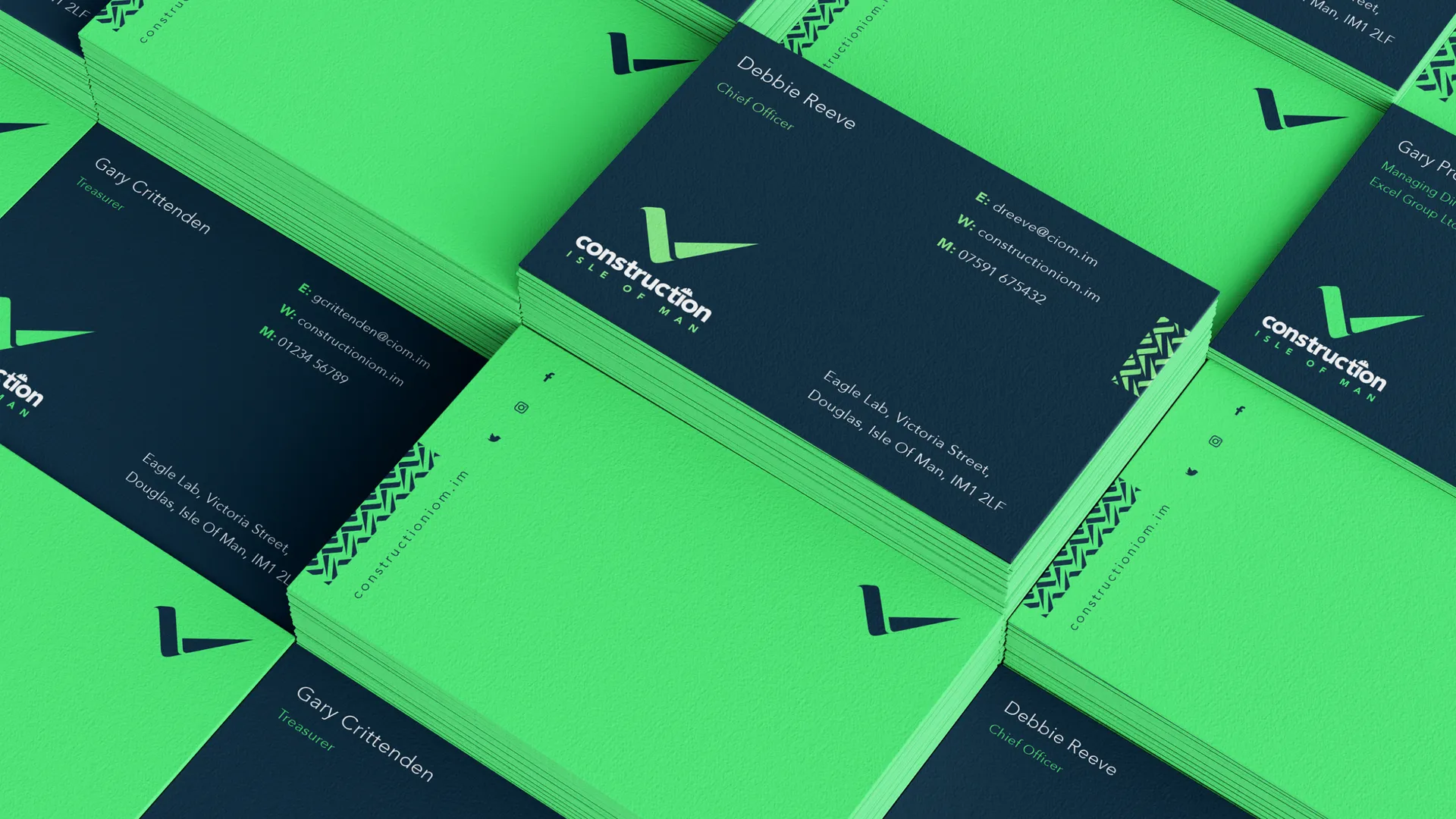 Stacks of Construction Isle of Man business cards designed by DotPerformance, showing the navy and green colourway with cards for Gary Crittenden and Debbie Reeve, based at Eagle Lab, Victoria Street, Douglas, Isle of Man